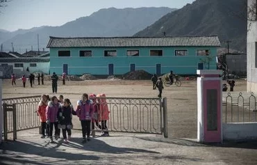 In a photo taken on November 18, 2017, North Korean children walk through a gate in a township north of Wonsan, Kangwon province. [Ed Jones/AFP]